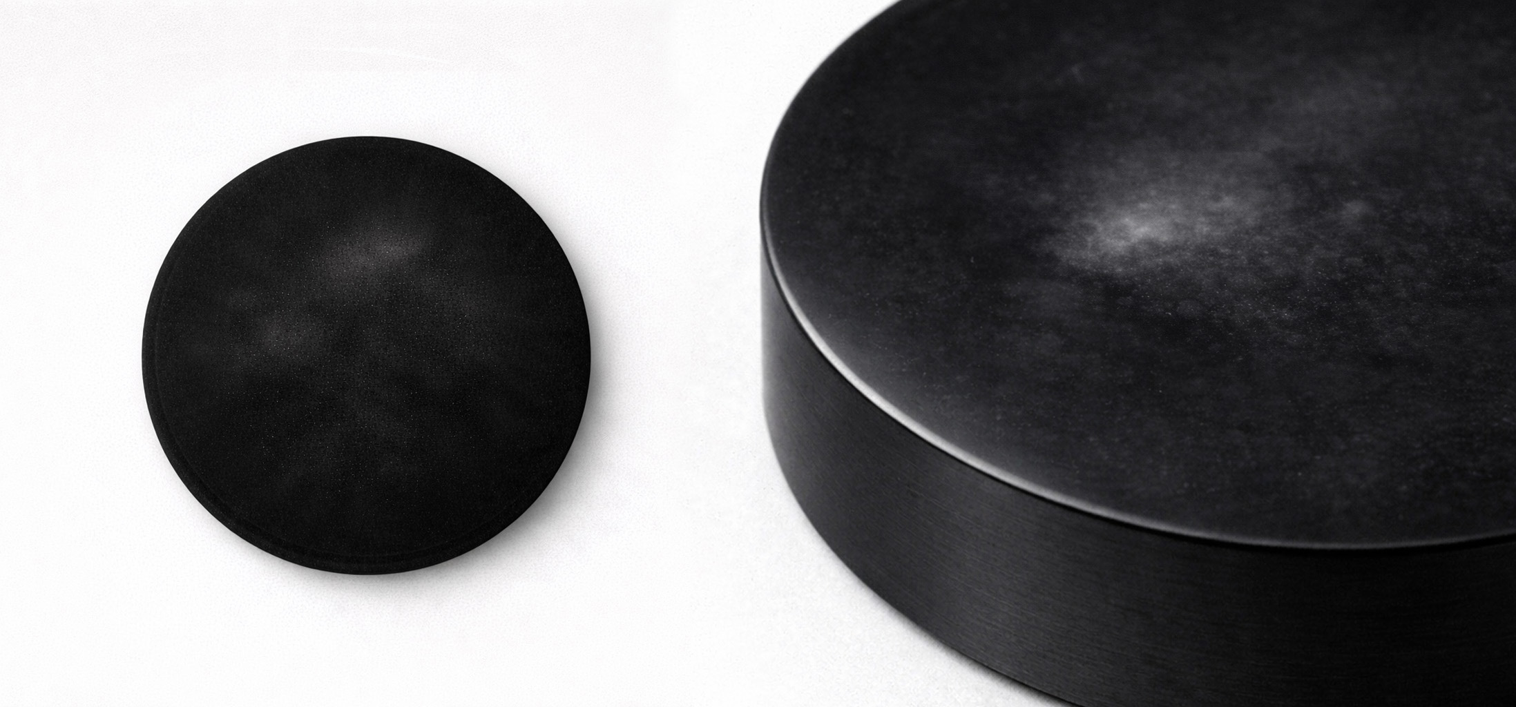 Top-down and macro studio views of the AGAR-7 microbial Host on a light grey background, showing a sealed black specimen disk with faint internal bloom and suspended surface-field disturbance